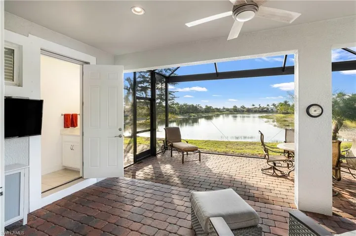 Sunroom / solarium featuring a water view, brick flooring, a ceiling fan, healthy amount of natural light, and recessed lighting