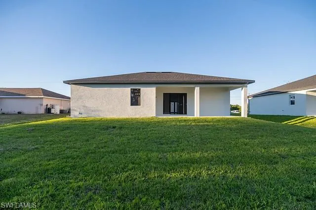 Back of property with a yard, stucco siding, and a patio area