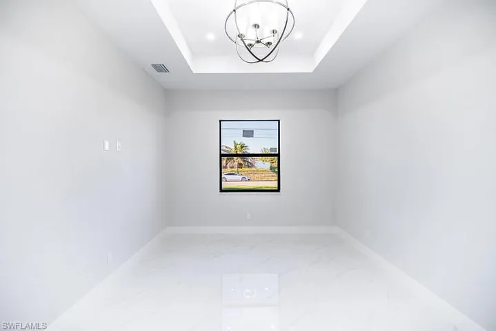 Unfurnished room featuring hanging lights and a raised ceiling