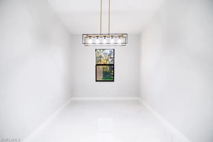 Unfurnished dining area with baseboards and light marble finish floors
