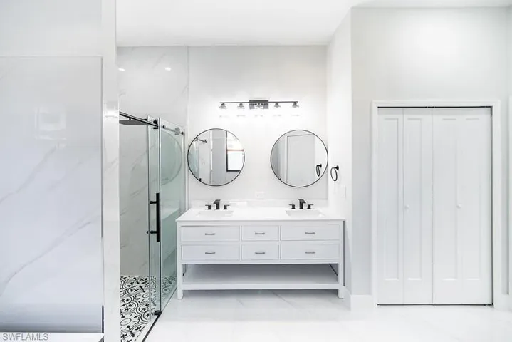 Full bath featuring double vanity, a closet, and a marble finish shower