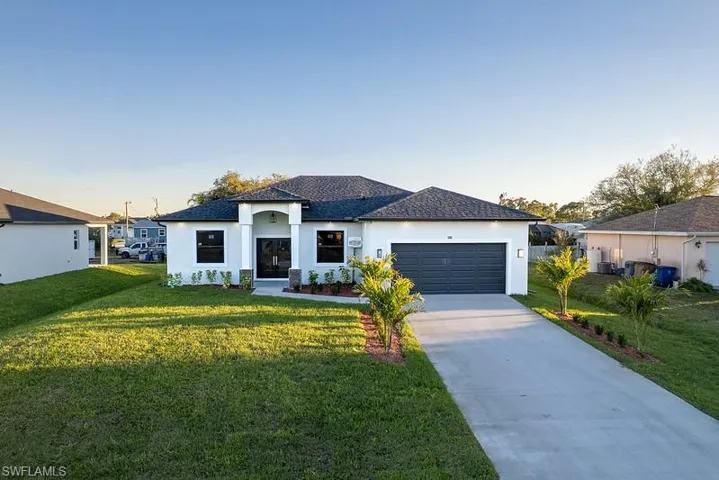View of front of house with a lawn, stucco siding, an attached garage, and concrete driveway