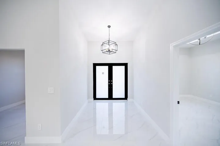Entryway featuring hanging lights, marble look tile flooring, and a high ceiling