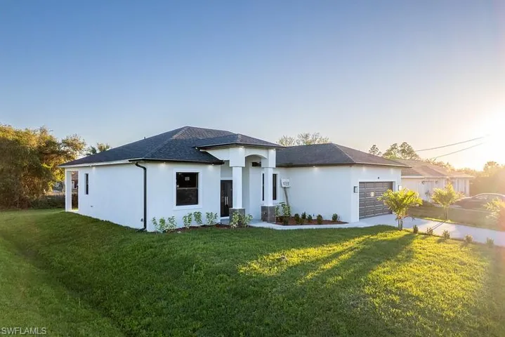 Prairie-style home featuring an attached garage, a front lawn, and stucco siding