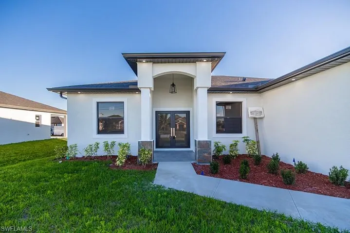 Doorway to property with a yard, french doors, and stucco siding