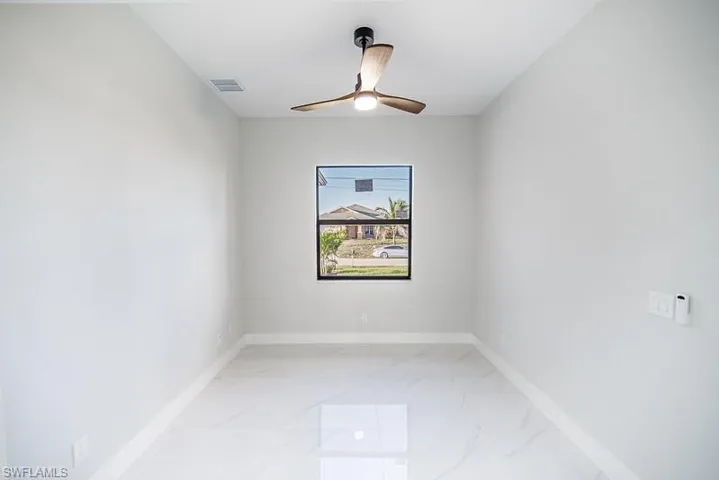 Spare room featuring a ceiling fan and baseboards
