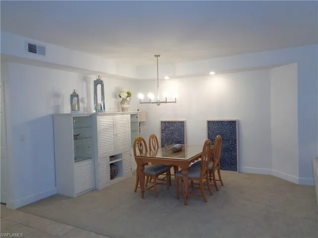 Dining room with hanging lights and light colored carpet