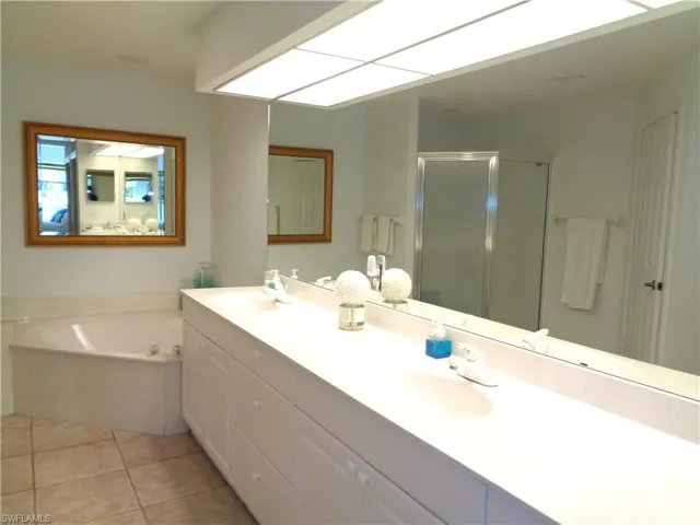Bathroom featuring double vanity, a stall shower, a bath, and light tile patterned floors