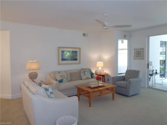 Living area featuring light colored carpet and ceiling fan