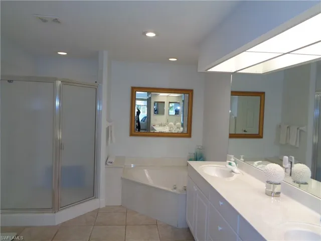 Bathroom with double vanity, a shower stall, a bath, light tile patterned floors, and recessed lighting