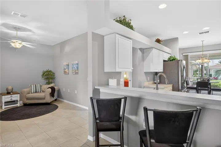 Kitchen with light countertops, white cabinetry, a chandelier, a breakfast bar, and light tile patterned flooring