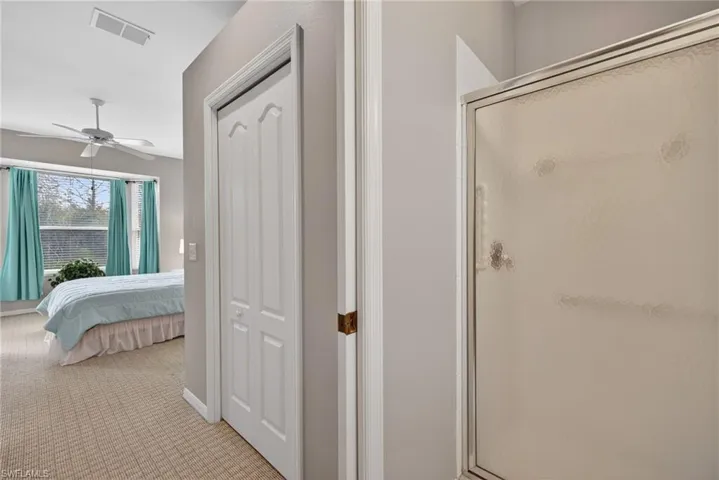 Ensuite bathroom featuring carpet floors, a stall shower, and ceiling fan