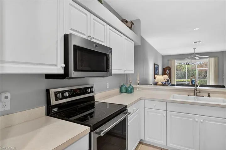 Kitchen featuring appliances with stainless steel finishes, light countertops, white cabinets, and ceiling fan