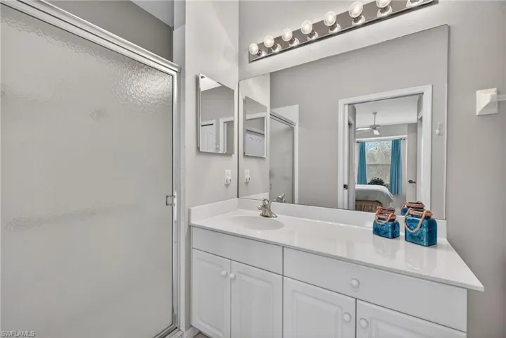 Ensuite bathroom featuring vanity, a shower stall, and a ceiling fan