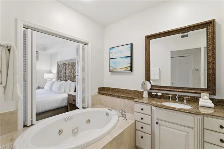 Ensuite bathroom with a whirlpool tub, vanity, and a closet