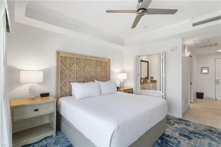 Bedroom with a tray ceiling, a ceiling fan, ornamental molding, and ensuite bathroom