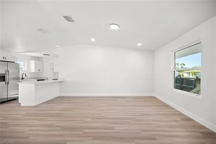 Unfurnished living room with light wood-style flooring and lofted ceiling