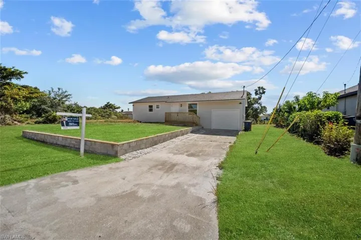 View of front of home featuring concrete driveway, a front lawn, an attached garage, and stucco siding