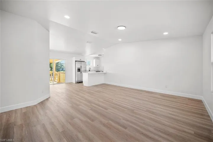 Unfurnished living room featuring light wood-style floors, recessed lighting, and vaulted ceiling