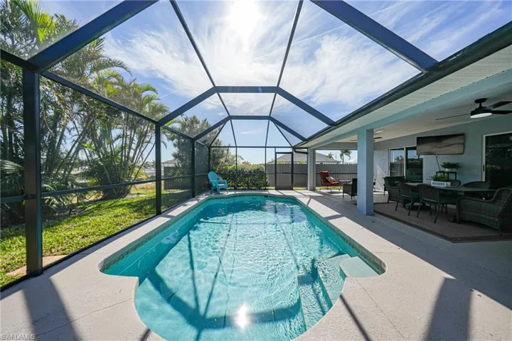View of pool featuring ceiling fan, a patio area, and glass enclosure