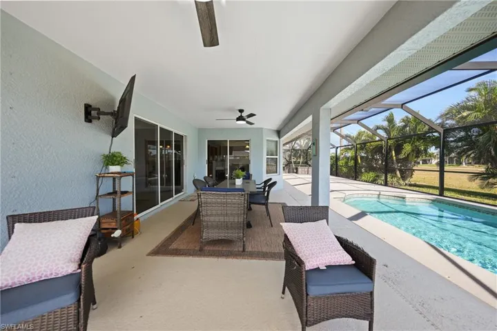 View of swimming pool with a patio, glass enclosure, and ceiling fan