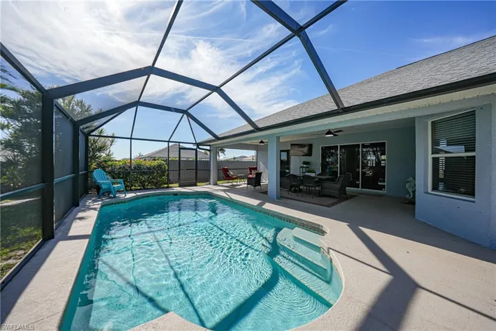 View of pool featuring a patio, glass enclosure, and ceiling fan