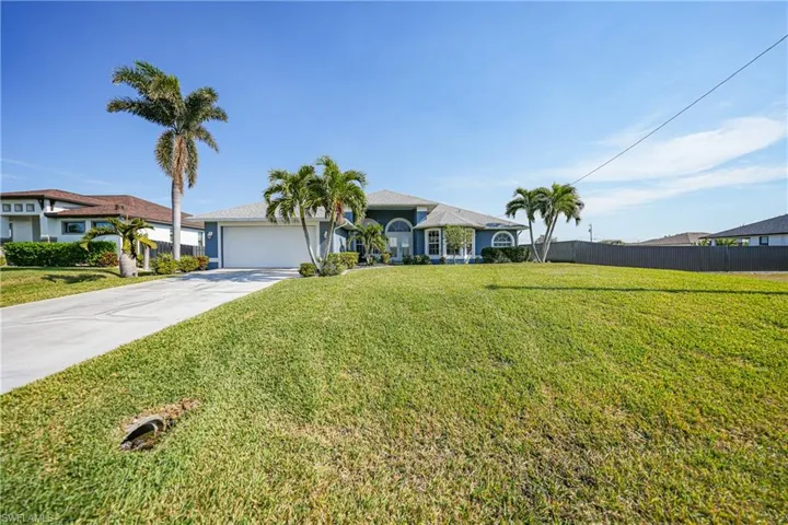 Ranch-style house featuring a garage and a front lawn
