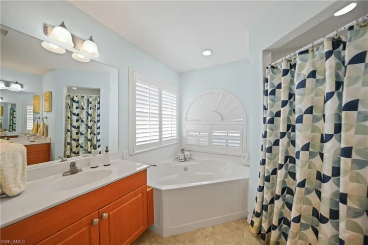 Bathroom featuring tile patterned flooring, vanity, and plus walk in shower