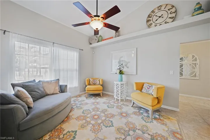 Tiled living room with ceiling fan and high vaulted ceiling
