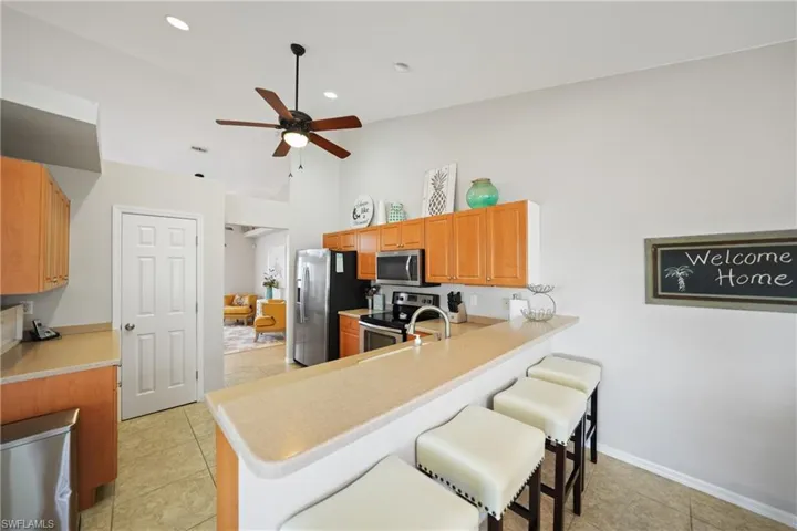 Kitchen with kitchen peninsula, appliances with stainless steel finishes, light tile patterned floors, and a breakfast bar area