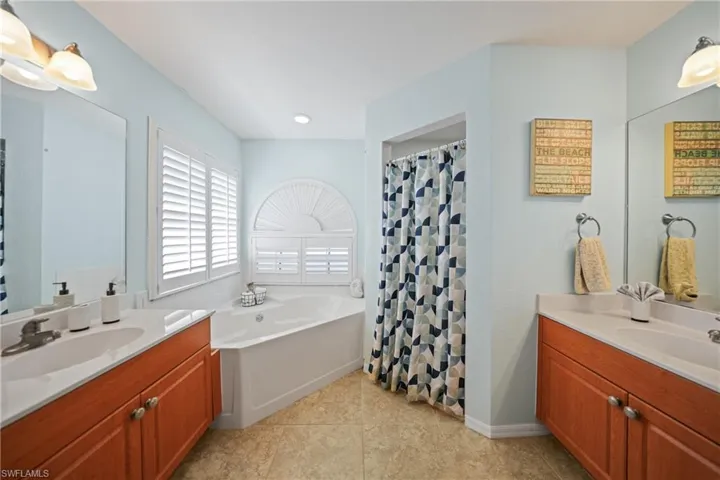Bathroom featuring tile patterned flooring, vanity, and plus walk in shower
