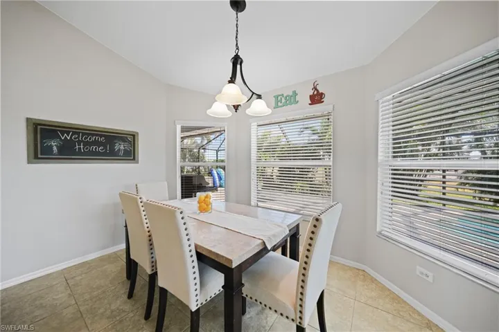 Dining space featuring an inviting chandelier, vaulted ceiling, and light tile patterned flooring