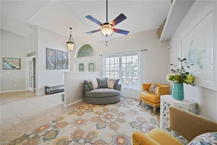 Tiled living room with french doors, ceiling fan, and lofted ceiling