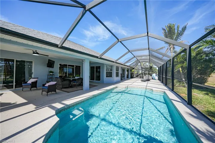 View of pool with ceiling fan, a patio area, and glass enclosure
