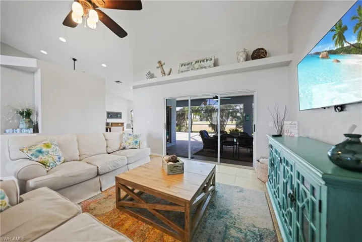 Living room featuring light tile patterned floors, ceiling fan, and lofted ceiling