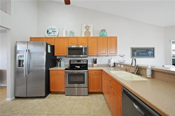 Kitchen featuring light tile patterned flooring, lofted ceiling, sink, and appliances with stainless steel finishes