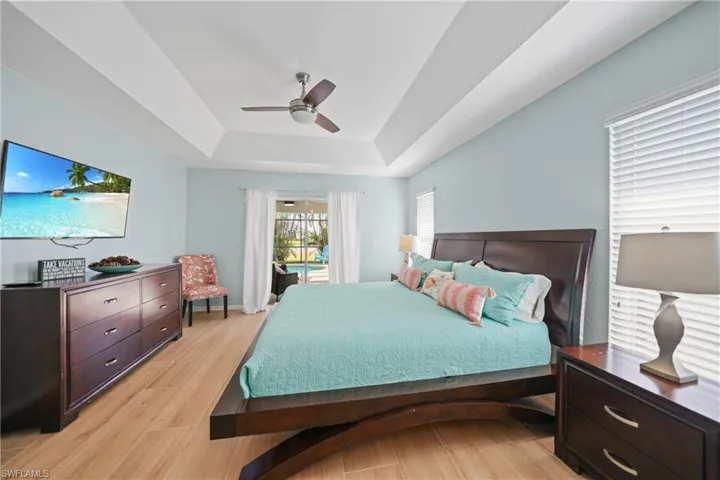Bedroom with a tray ceiling, ceiling fan, and light hardwood / wood-style floors