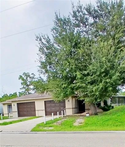 View of front of house with a front yard, stucco siding, a garage, and driveway