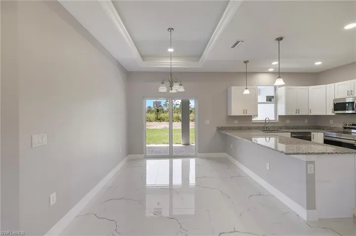Kitchen featuring marble finish floor, a peninsula, baseboards, a sink, and stainless steel appliances