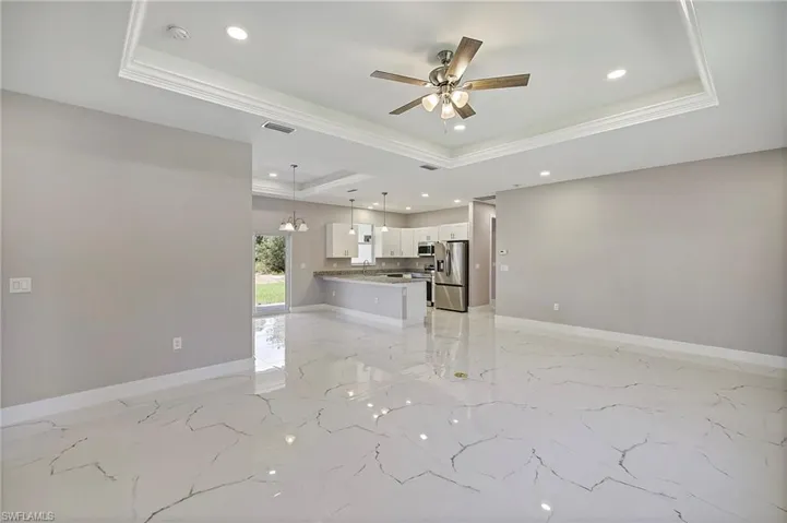 Empty room featuring recessed lighting, ceiling fan, visible vents, and a raised ceiling