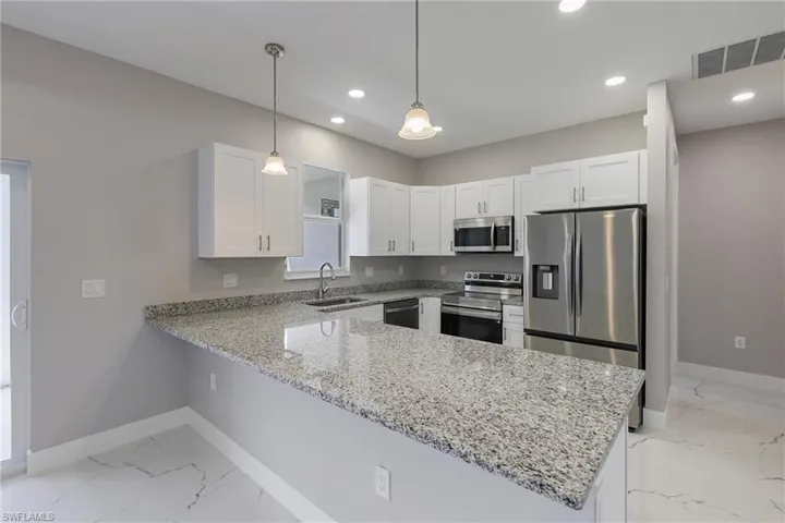 Kitchen with visible vents, a sink, a peninsula, marble finish floor, and stainless steel appliances