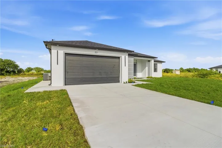 Prairie-style home featuring a front lawn, stucco siding, concrete driveway, and an attached garage