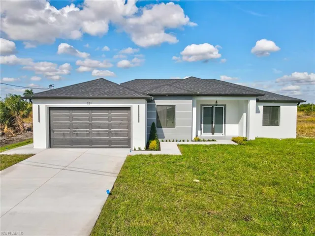 View of front of home featuring stucco siding, a front yard, driveway, and an attached garage