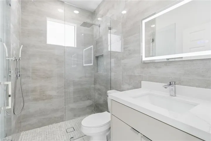 Bathroom featuring vanity, a shower stall, and tile walls