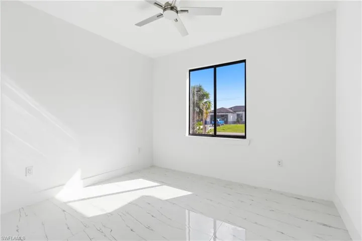 Spare room featuring light marble finish floors and ceiling fan