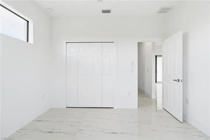 Unfurnished bedroom featuring light marble finish flooring and a closet