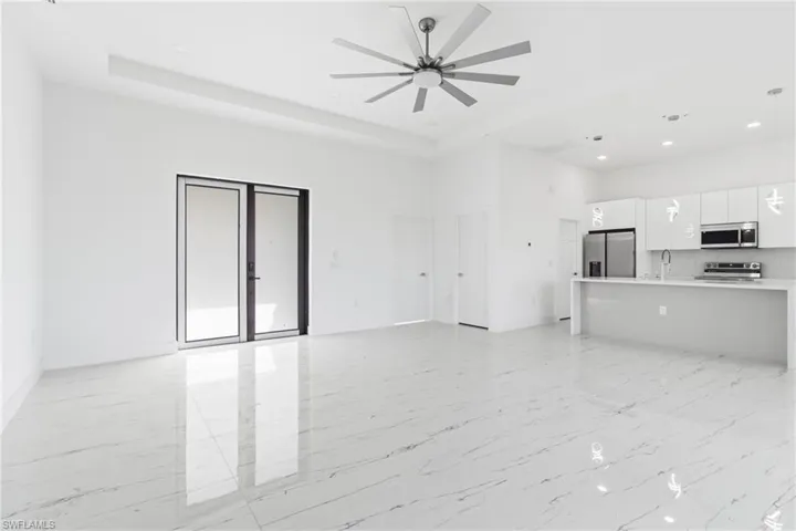 Unfurnished living room with recessed lighting, light marble finish flooring, a ceiling fan, and a high ceiling