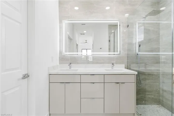 Full bath with double vanity and a shower stall