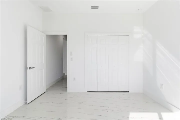 Unfurnished bedroom featuring light marble finish flooring and a closet