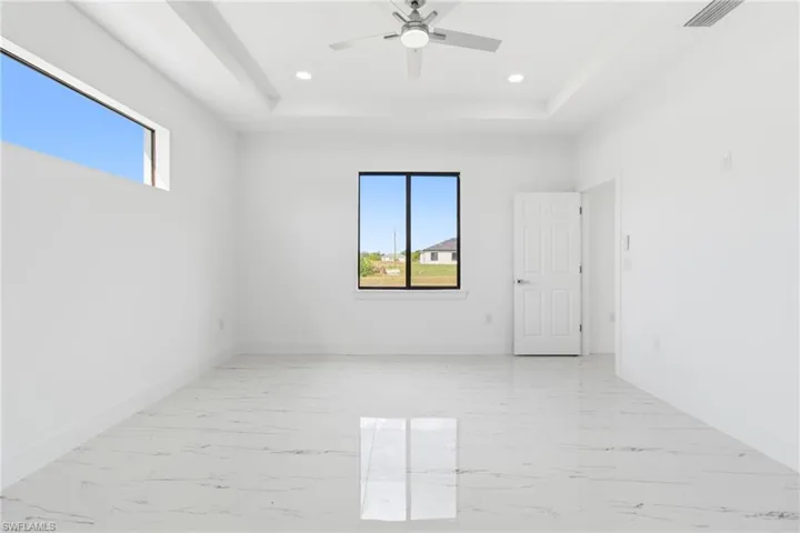 Unfurnished room featuring light marble finish floors, a raised ceiling, ceiling fan, and recessed lighting